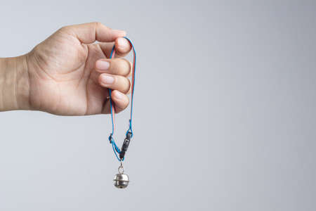 Hand holding pet collar with bell for dog and cat on white backgroundの写真素材