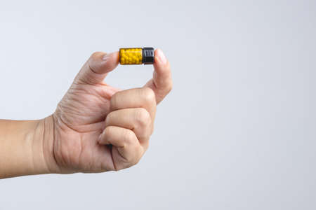 Hand holding traditional Asian herbal medicine pills in a small sunscreen bottle on white backgroundの写真素材