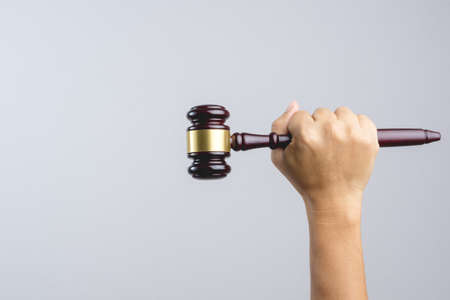 Hand holding wooden judge's gavel as a law or justice sign on white backgroundの写真素材