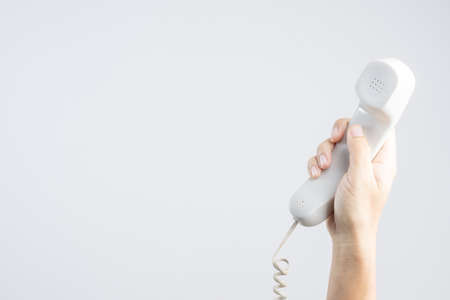 Hand holding home or office telephone with line on white backgroundの写真素材