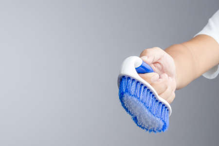 Hand holding new blue floor brush with plastic handle on white backgroundの写真素材