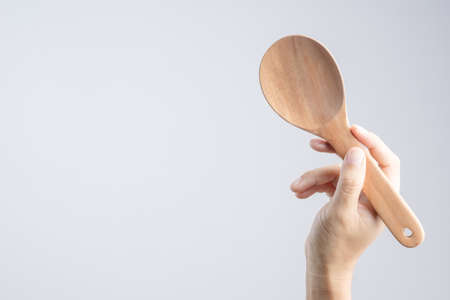 Hand holding wooden ladle or big spoon on white backgroundの写真素材