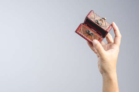 Hand holding small leather treasure chest box on white background
