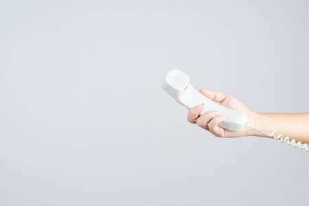 Hand holding home or office telephone with line on white backgroundの写真素材