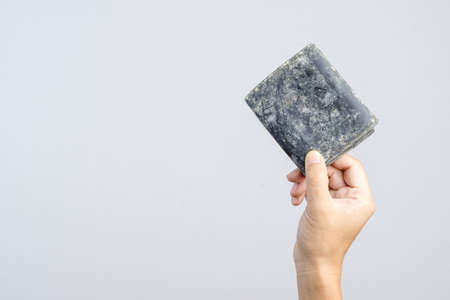 Hand holding empty old leather pouch or man wallet with mold and fungus on white backgroundの写真素材