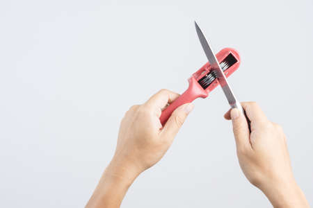 Hand holding knife blade sharpener, accessory for the kitchen on white backgroundの写真素材