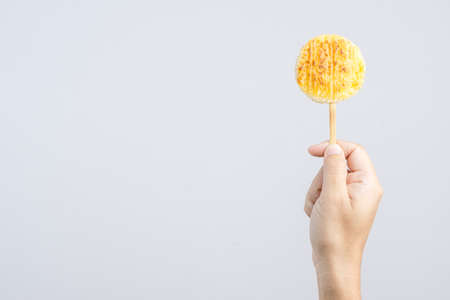 Hand holding grilled sticky rice dipped in egg or Kaow Jei, a Thai local food on white backgroundの写真素材