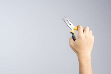 Hand holding needle nose or pointy pliers for universal repair and construction on white backgroundの写真素材