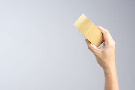 Hand holding brown packaging tape roll on white backgroundの写真素材