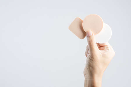 Hand holding face sponge puff for cosmetic on white backgroundの写真素材