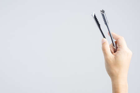 Hand holding steel ice tongs on white backgroundの写真素材