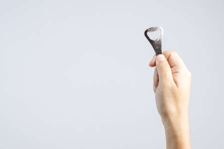 Hand holding classic bottle cap opener made of steel on white background