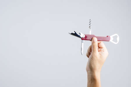 Hand holding pocket universal bottle opener with short knife for multi functions on white backgroundの写真素材