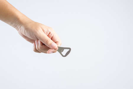 Hand holding classic bottle cap opener made of steel on white backgroundの写真素材