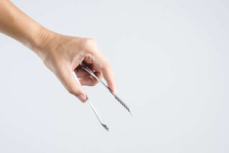 Hand holding steel ice tongs on white backgroundの写真素材