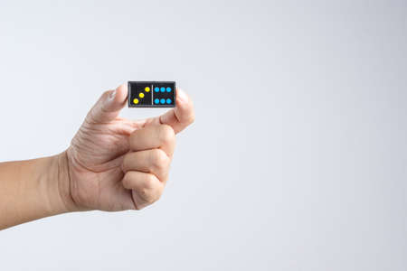 Hand holding a piece of plastic domino pieces on white backgroundの写真素材