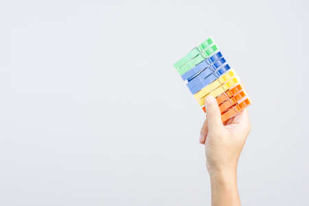 Hand holding row of   colorful plastic cloth clamp or clip on white backgroundの写真素材