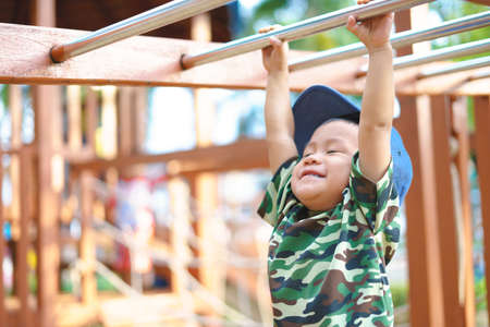 Asian boy about 1 year and 9 months in military suit playing at kid training playground for muscle developmentの写真素材