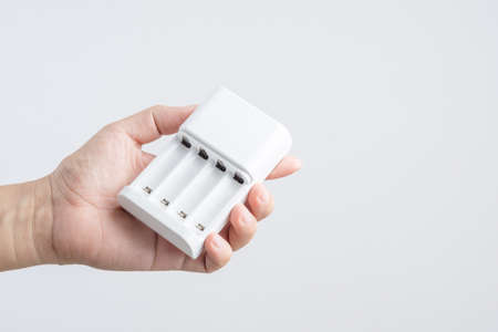 Hand holding battery charger with for both AA and AAA sizes on white backgroundの写真素材