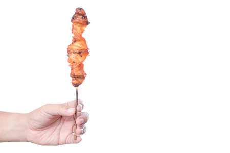 Hand holding charcoal grilled or roasted chicken butt on stick, a traditional Thai street food on white backgroundの写真素材