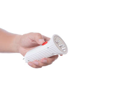 Hand holding rechargeable flashlight with wall charge plug on white background