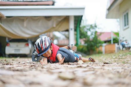Asian boy about 2 years is riding baby balance bike and fall, get up on his own, playing and learning conceptの写真素材