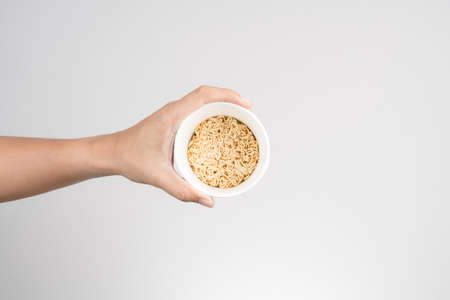 Hand holding instant noodle cup on white background