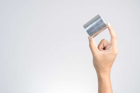 Hand holding adhesive aluminum foil tape for padding on white backgroundの写真素材