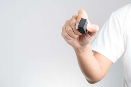 Hand holding black pencil eraser rubber with used or scrach mark on white backgroundの写真素材