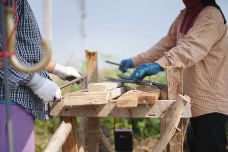 Asian worker bending metal at house construction site using only hands and simple equipmentの写真素材