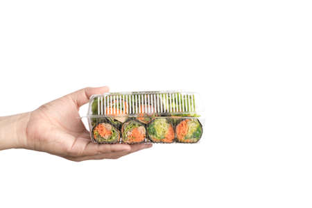 Hand holding food plastic box of hydroponics vegetable salad roll wrapped by seaweed on white backgroundの写真素材