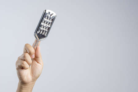 Hand holding grater for peeling fruits and vegetables on white backgroundの写真素材
