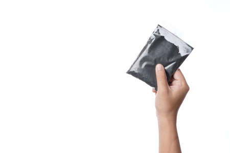 Hand holding plastic zipper bag of charcoal powder on white backgroundの写真素材