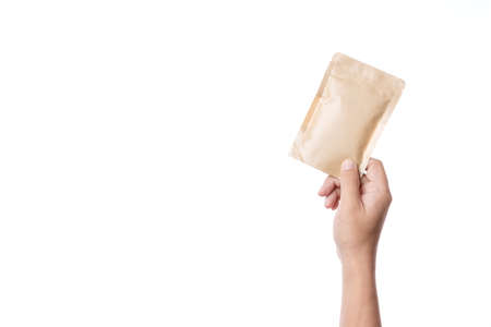Hand holding brown paper packaging bag with zipper lock on white backgroundの写真素材