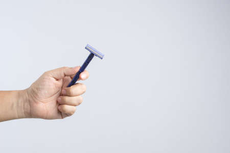 Hand holding disposable and cheap shaving razor on white backgroundの写真素材