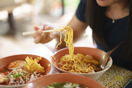 Asian woman eating hot and spicy yellow noodle, many food at onceの写真素材