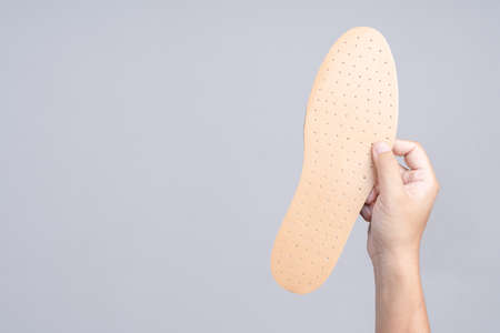 Hand holding replacement shoe sole on white backgroundの写真素材