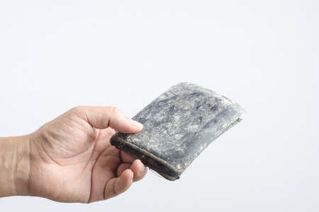 Hand holding empty old leather pouch or man wallet with mold and fungus on white backgroundの写真素材