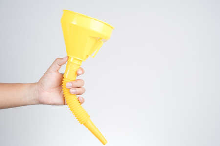 Hand holding yellow plastic funnel cone for water or fluid transfer on white background
