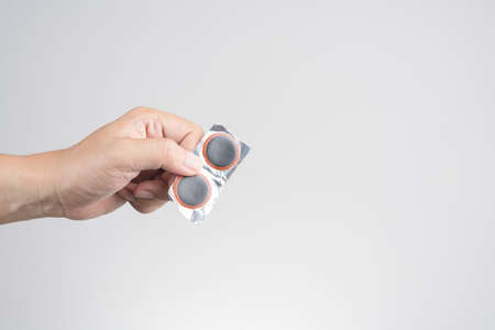 Hand holding bicycle or bike tube patch, an emergency repair kit on white background