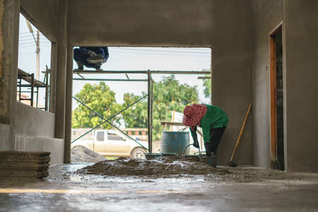 Asian worker labor working and mixing concrete cement by hoe at house construction siteの写真素材