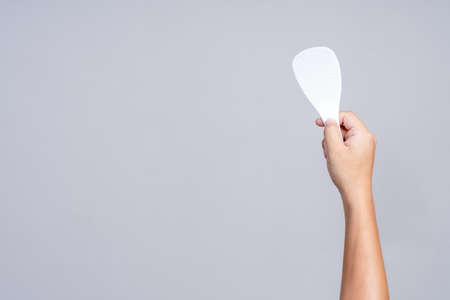 Hand holding hot resistance plastic for rice paddle spoon or ladle on white backgroundの写真素材