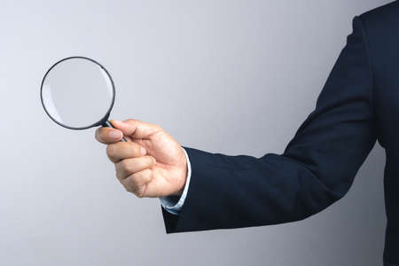 Business man hand holding magnifier for inspection on white background