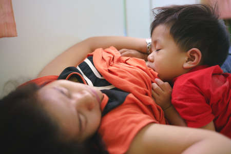 Asian boy about 2 year and 3 months sleeping while breastfeeding by his motherの写真素材