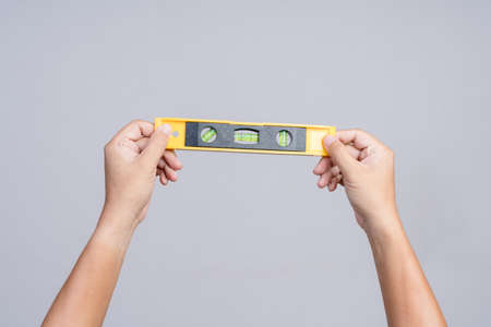 Hand holding spirit level tool for building or construction on white background
