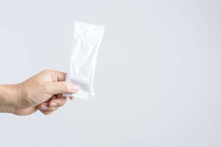 Hand holding new razor in small plastic bag on white backgroundの写真素材