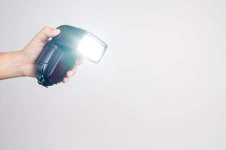 Hand holding camera  external flash speed light on white backgroundの写真素材