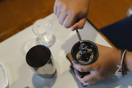 Hand crushing roasted berries beans with coffee grinder