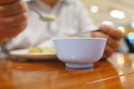 Round fat hand eating Asian rice and  food with fork and spoonの写真素材