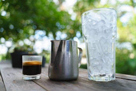 Coffee with milk in silver jug for making iced latte drinkの写真素材